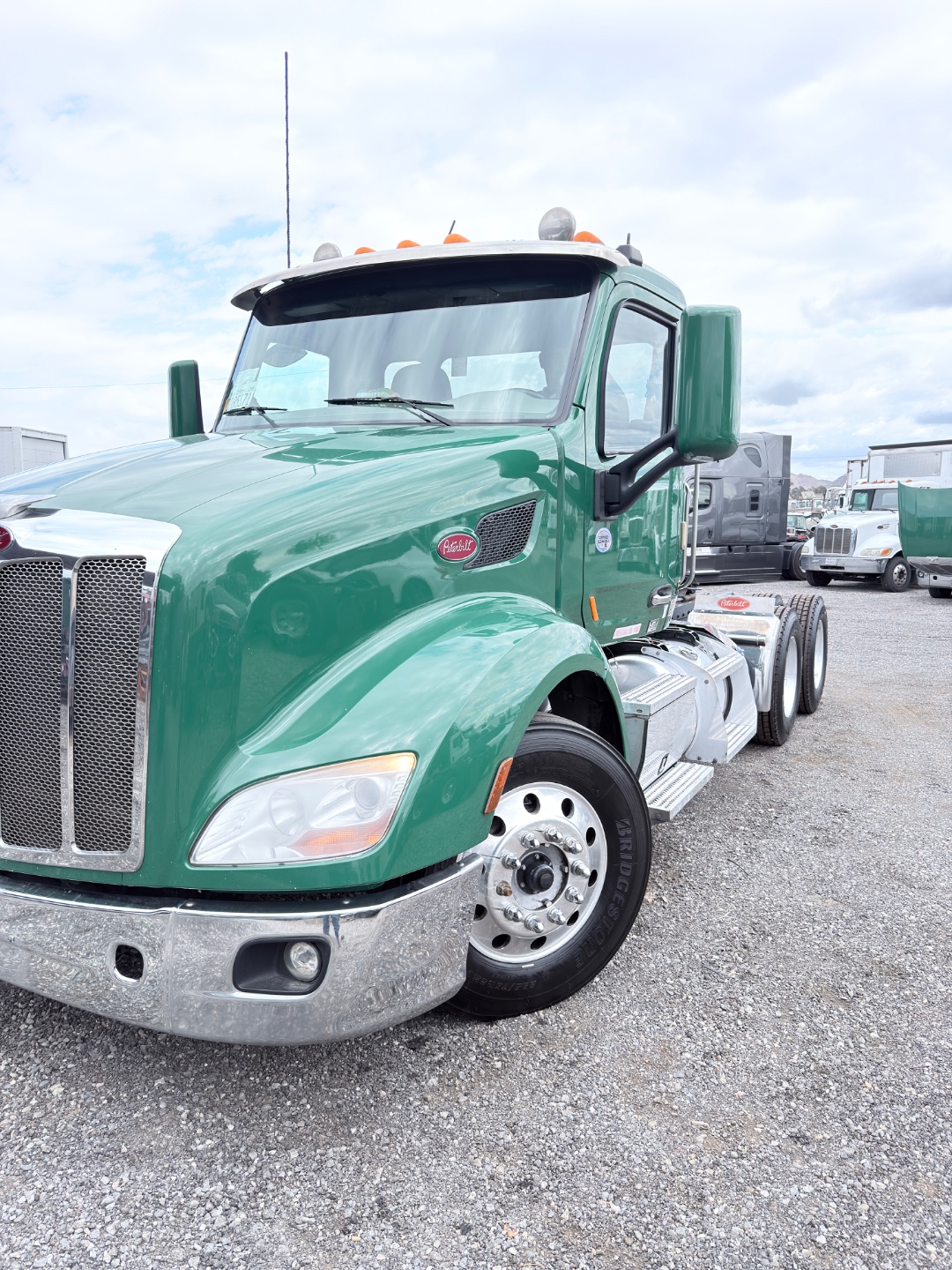 Green Peterbilt truck close-up showing cab, chrome, and yard equipment